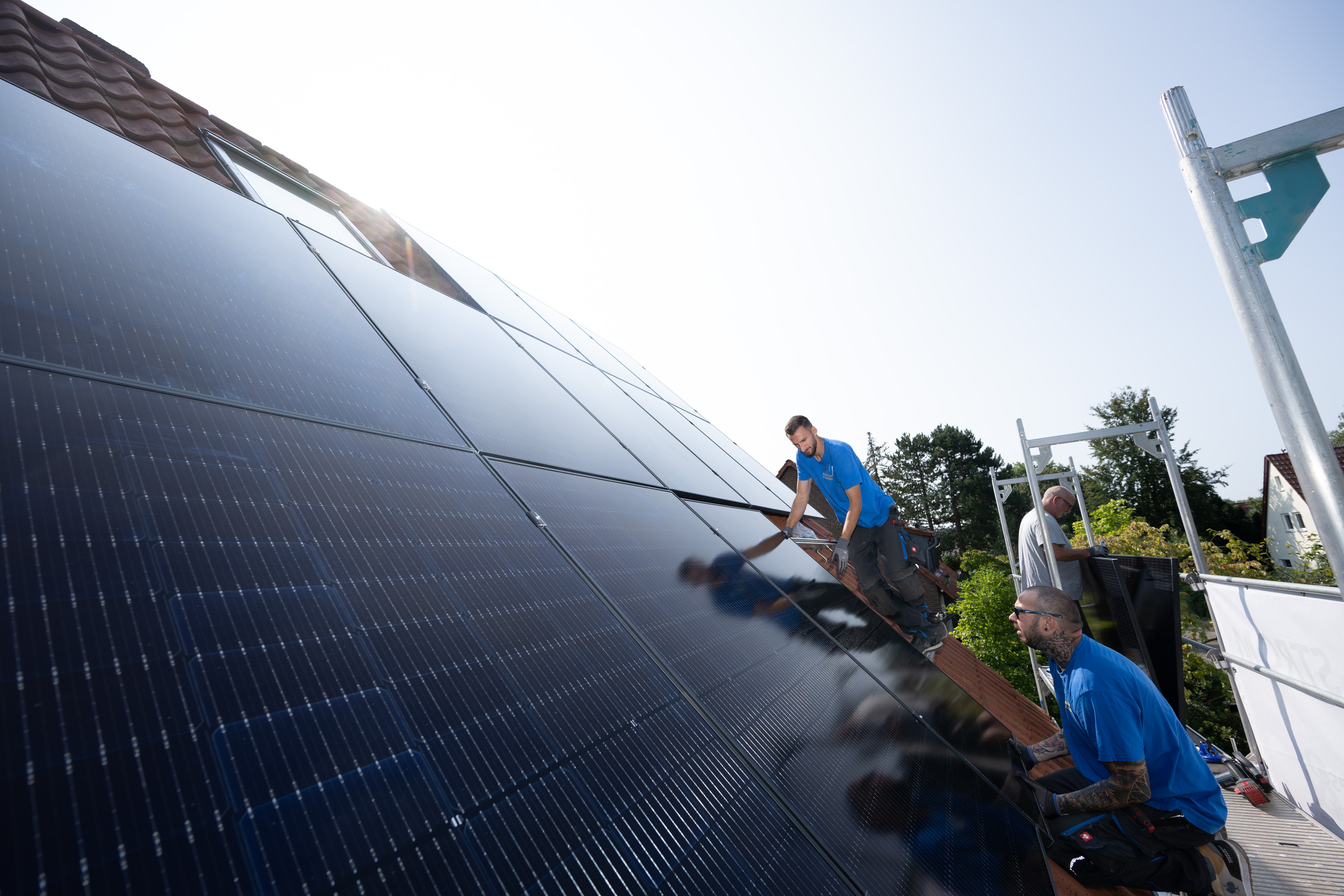 Mehrere Handwerker installierern Solarmodule auf einem Einfamilienhaus